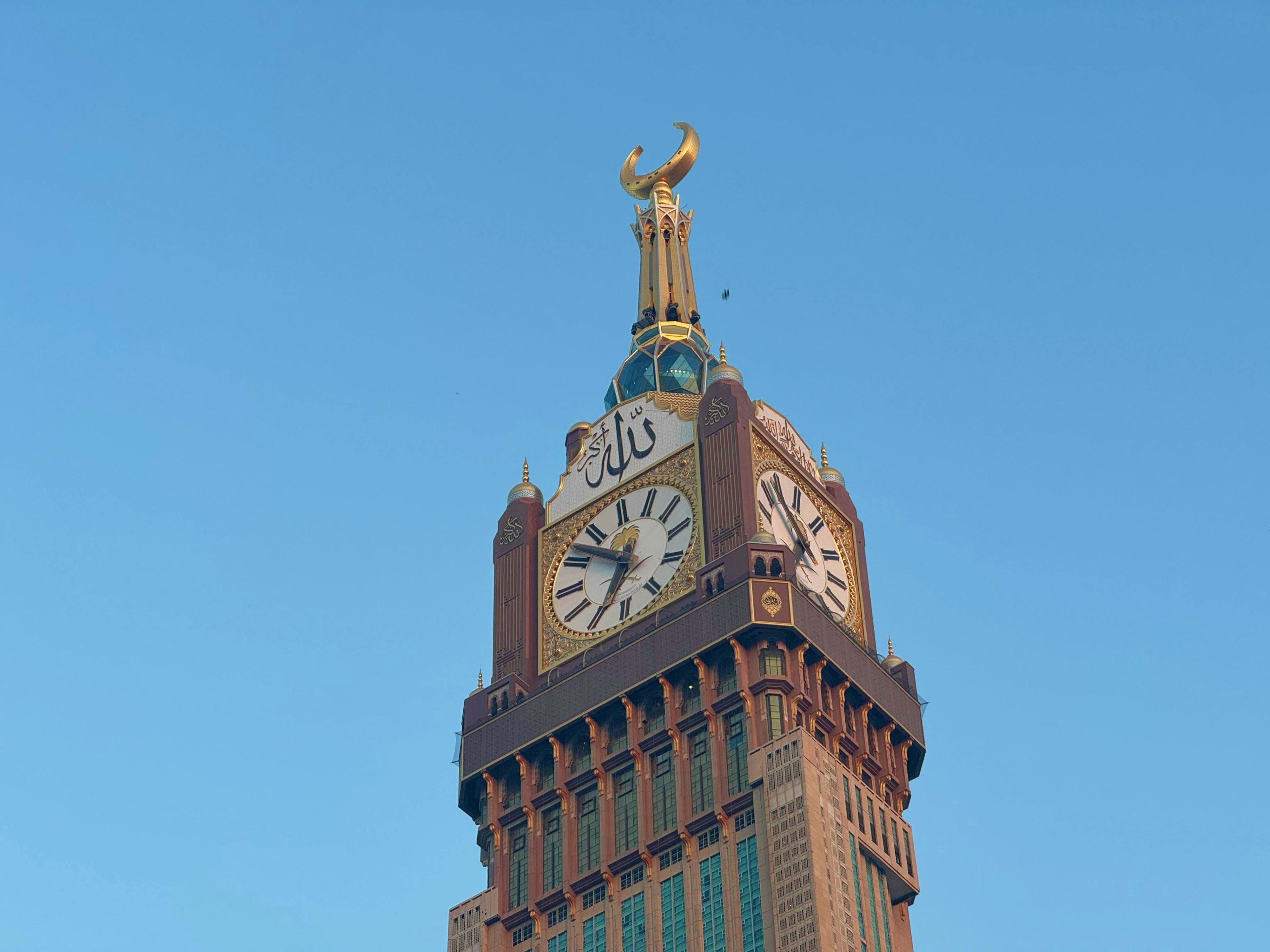 Saudi Arabia Historic clock tower with golden horns on top, Islamic architecture and ornate clock face against clear blue sky in Saudi Ara